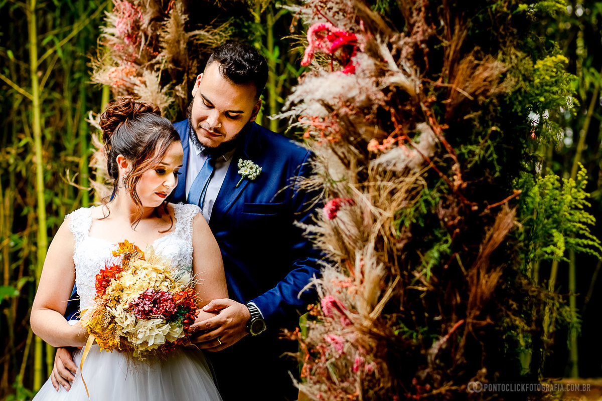 novia segurando o buque noivo abraçando a noiva por tras debaixo do arco de flores embaixo do arco de flores do espeaço laforet