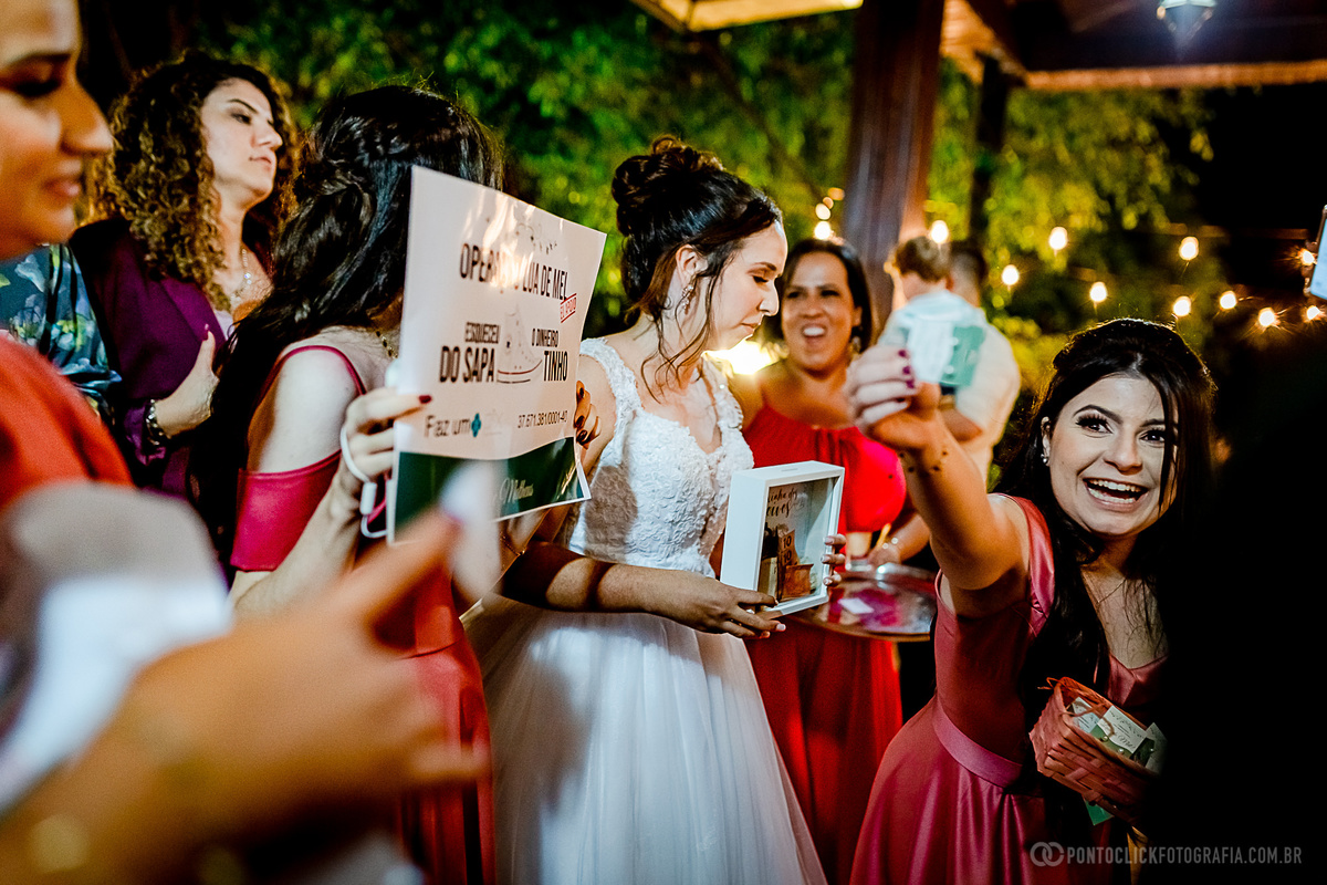 noiva e amigas sorrindo e segurando uma caixa com dinheiro