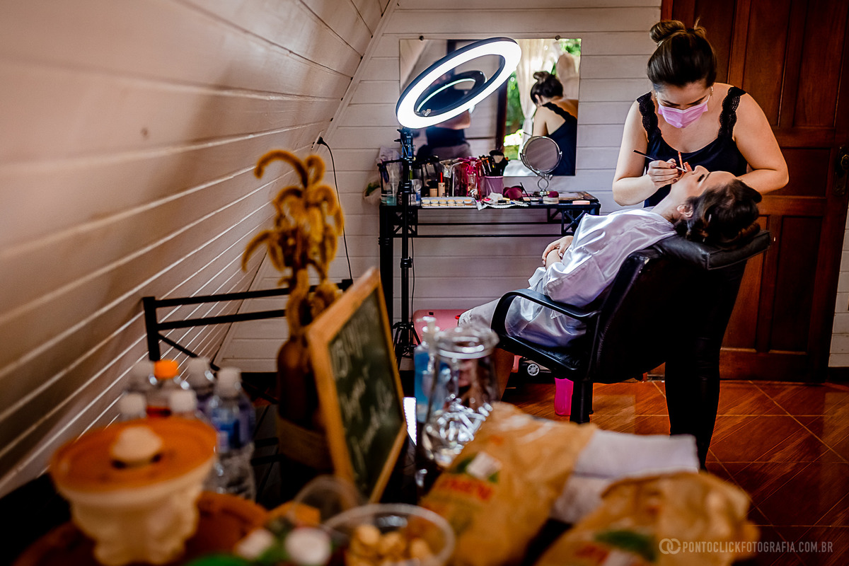 maquiadora maquiando a noiva sentada na cadeira de maquiar