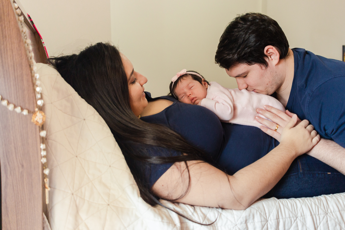 Foto dos pais com filha no colo dentro do quarto de menina na zona leste da cidade de São Paulo