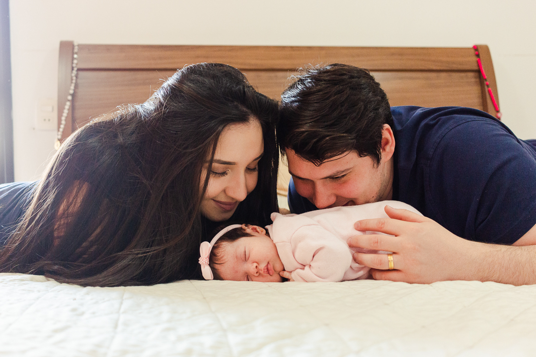 Foto dos pais com filha no colo no ensaio em casa zona leste da cidade de São Paulo