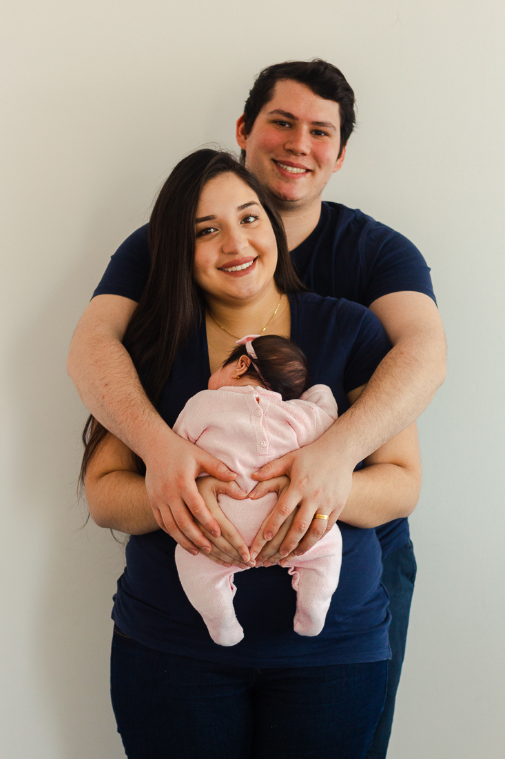 Pais de menina segurando no colo no ensaio em casa realizado na cidade de São Paulo