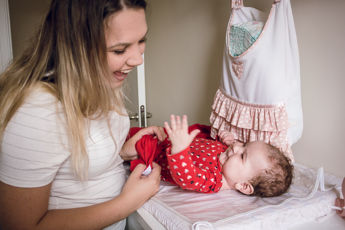 Foto vestindo roupa na filha bebe após o banho no quarto