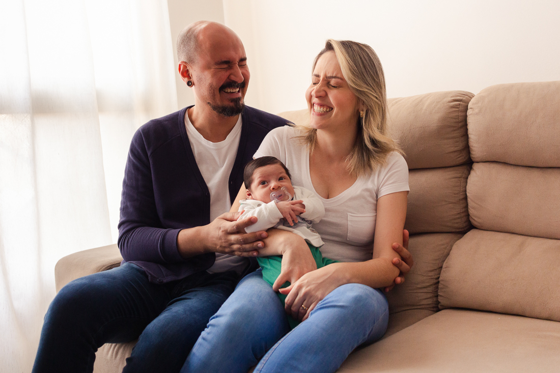 Pais de menino sorrindo com alegria no ensaio de família lifestyle em casa, no bairro da Vila Ré, zona leste de SP. 