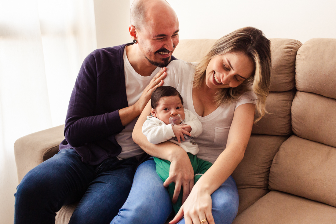 Pais de menino sorrindo com alegria no ensaio de família lifestyle em casa, no bairro da Vila Ré, zona leste de SP. 
