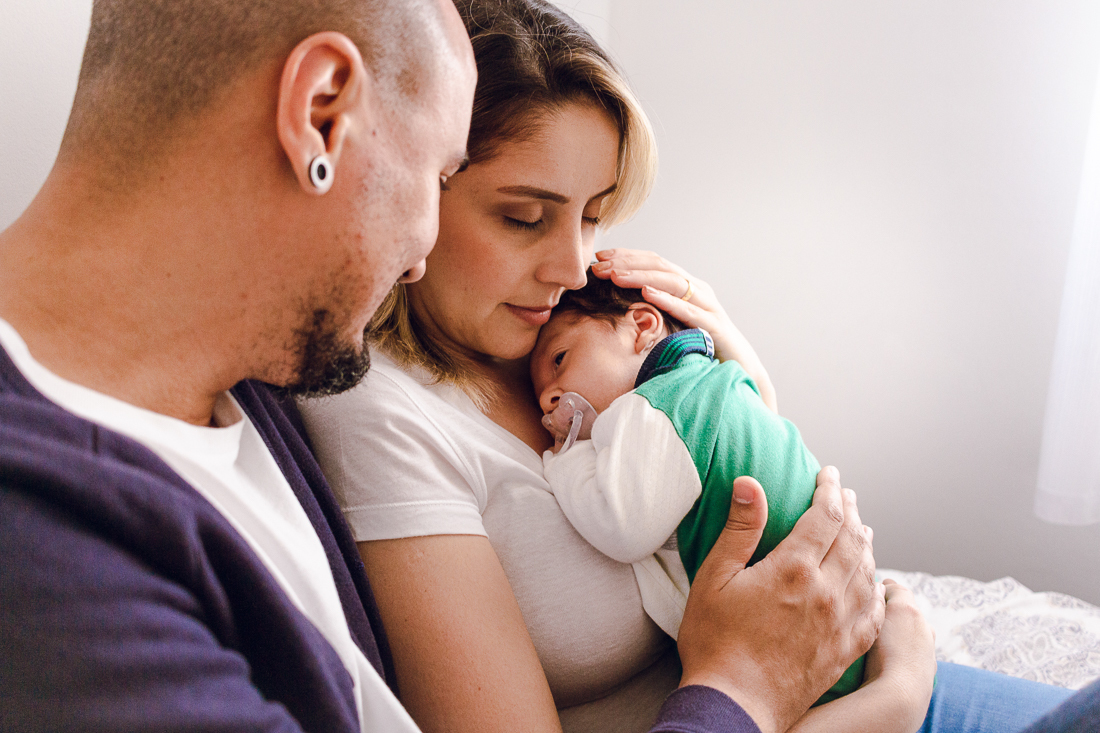 Pais de menino segurando bebê no colo no ensaio de família lifestyle em casa, no bairro da Vila Ré, zona leste de SP. 