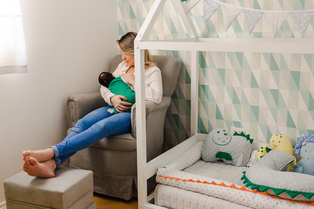 Mamãe de primeira viagem amamentando o filho bebe no quarto, no ensaio de família em casa, na cidade de São Paulo