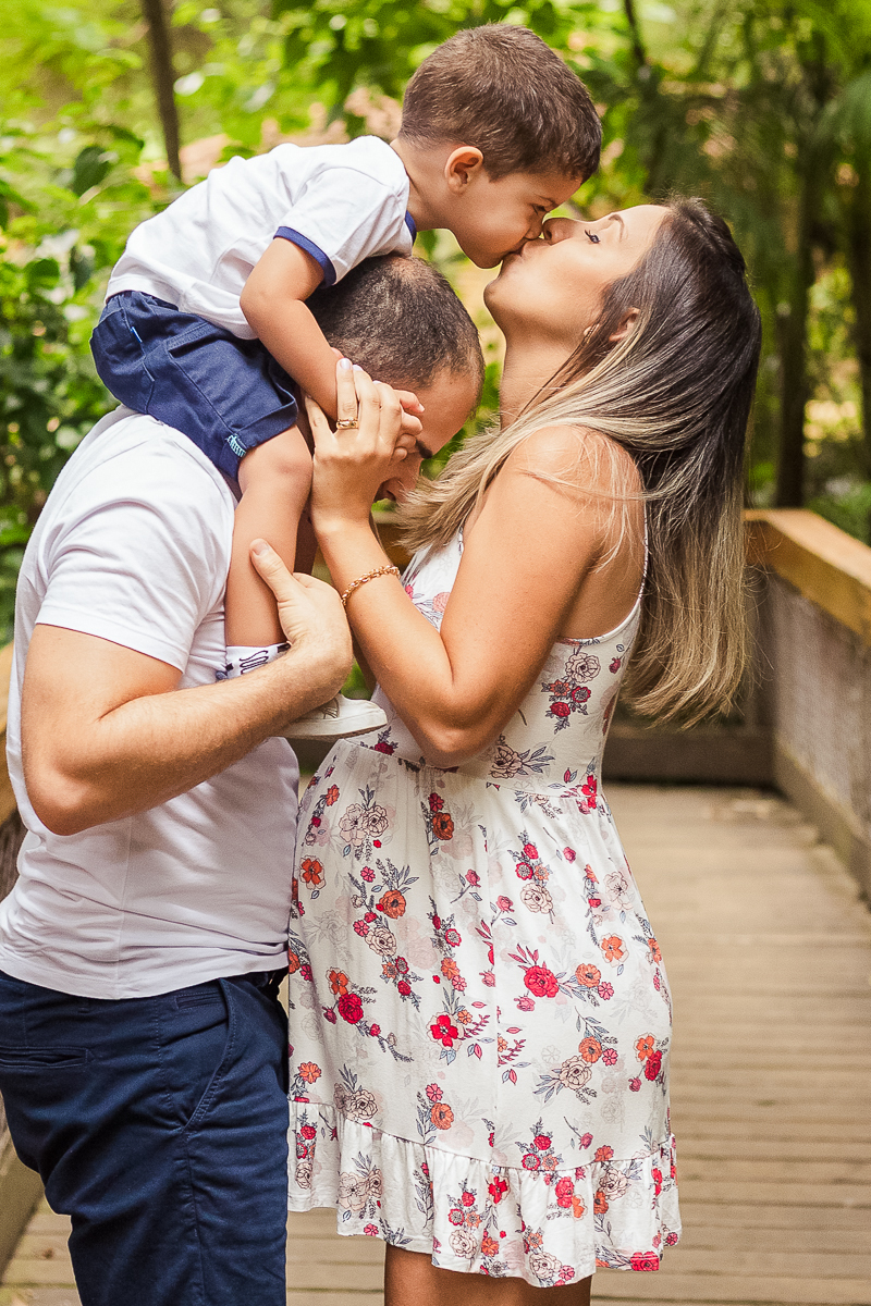 Foto de gestante mãe e filho dando beijo na boca no ensaio externo no parque da agua branca na cidade de São Paulo