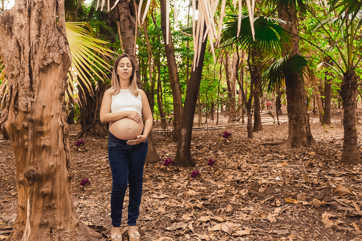 Foto de gestante com mão na barriga no ensaio externo no parque da agua branca na cidade de São Paulo