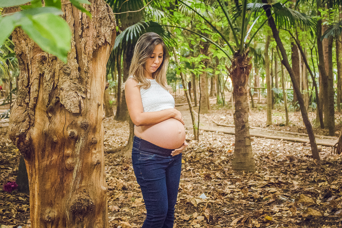 Foto de gestante com mão na barriga no ensaio externo no parque da agua branca na cidade de São Paulo