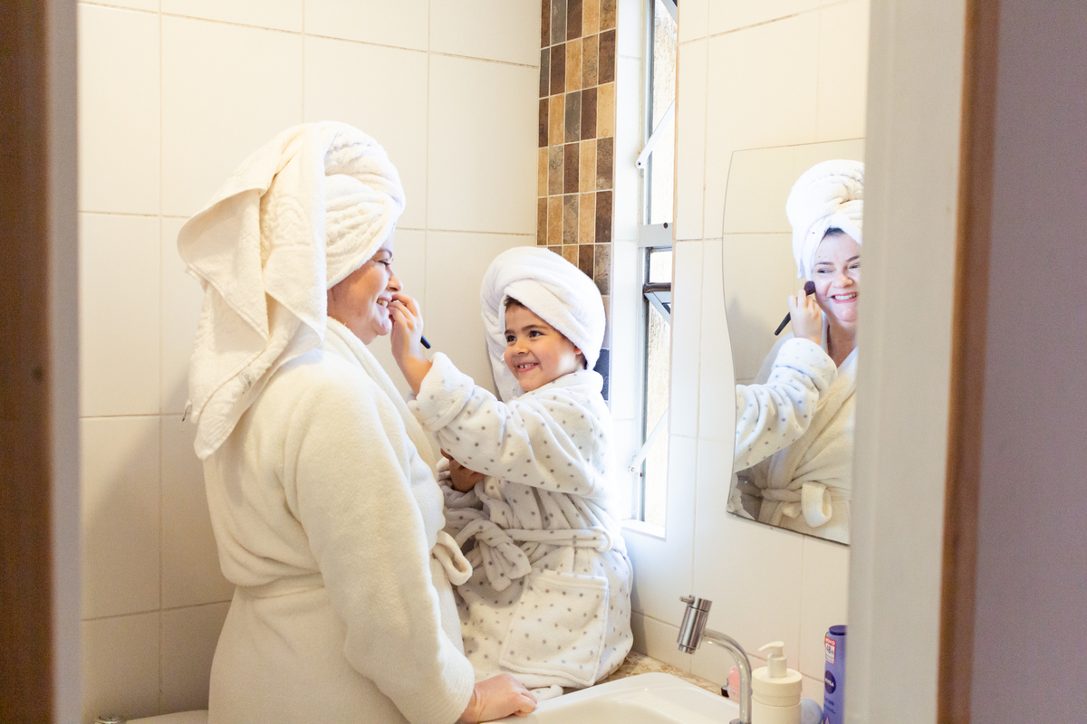 Mãe e filhas se maquiando no banheiro de casa  depois do banho no ensaio de família na cidade de São Paulo