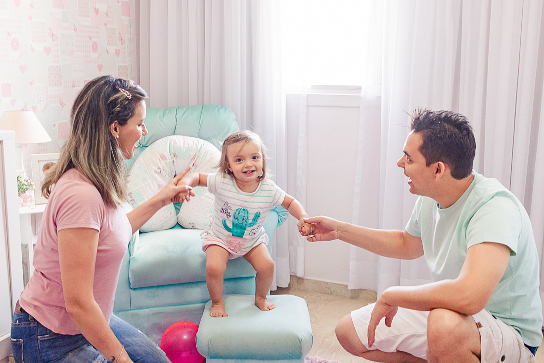 foto de pais brincando de pular com a filha no quarto na cidade de São Paulo.