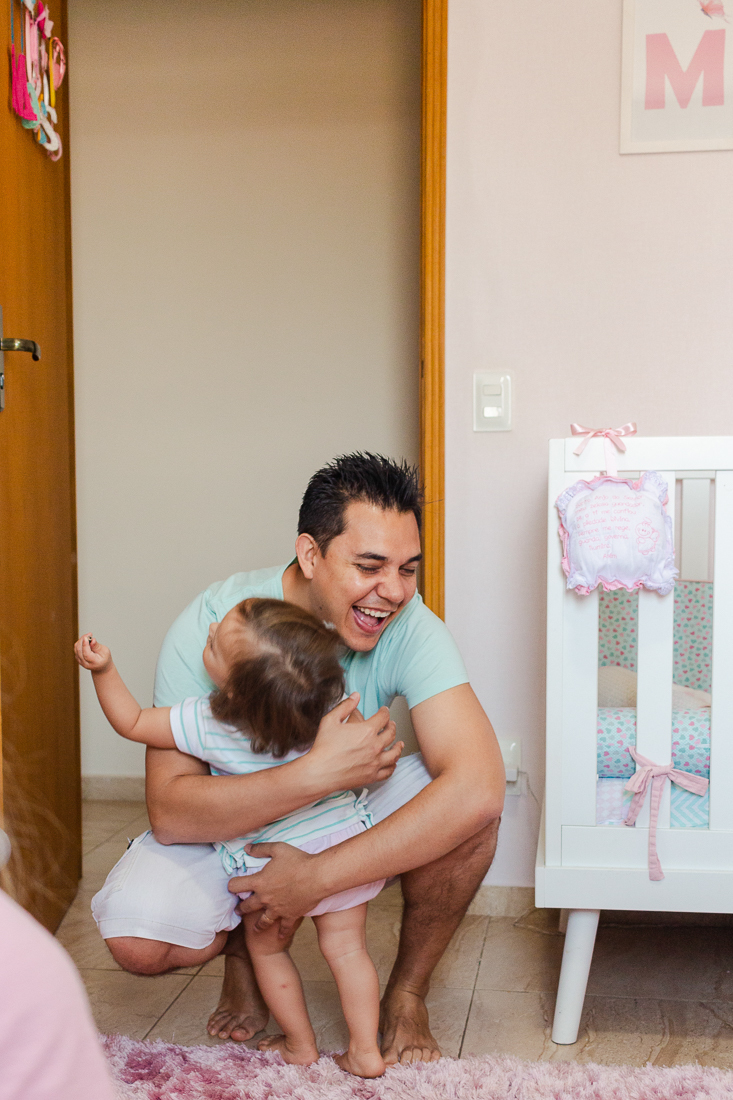 Pai abraçando filha no quarto rosa de menina na cidade São Paulo