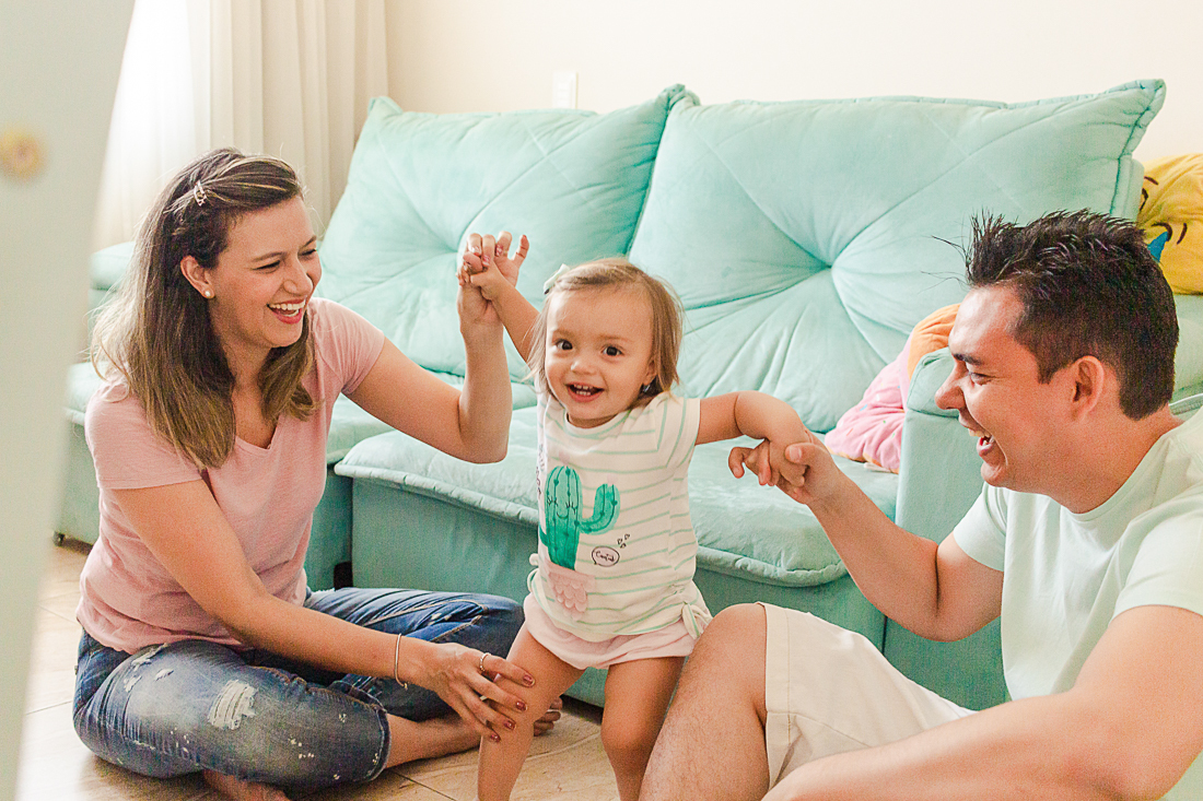 Pais brincando com a filha na sala de casa no ensaio de família na cidade de São Paulo