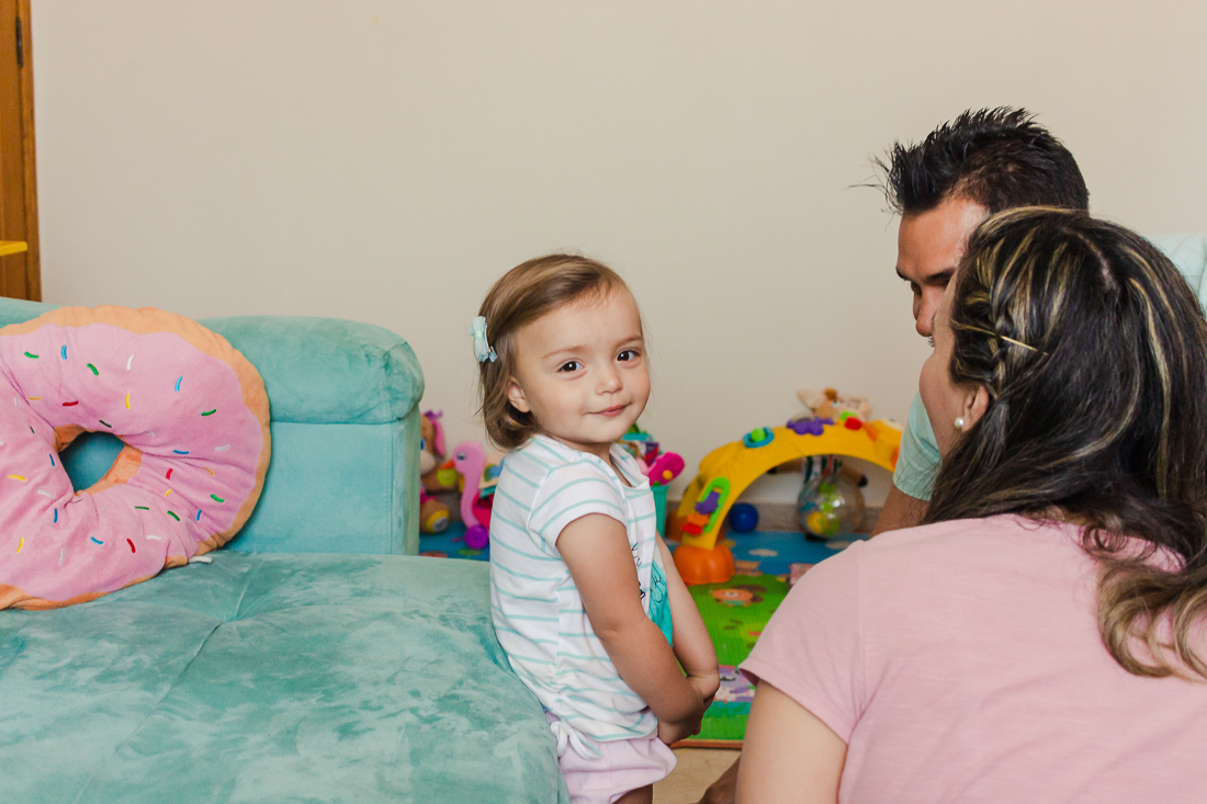 Pais brincando com a filha na sala de casa no ensaio de família na cidade de São Paulo