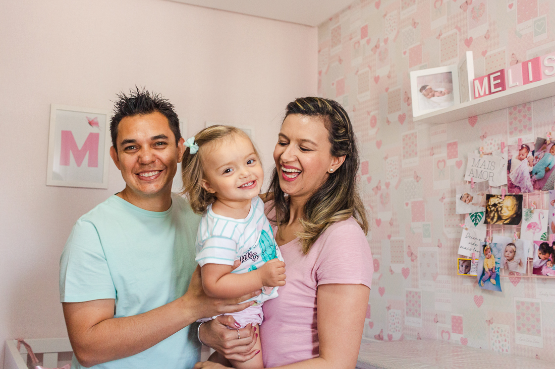 Foto de pais e filha no quarto sorrindo