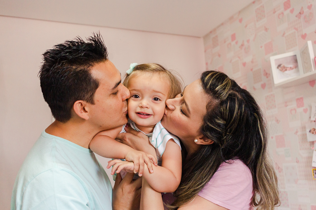 Papais beijando a filha no quarto no ensaio de família na cidade de São Paulo - SP