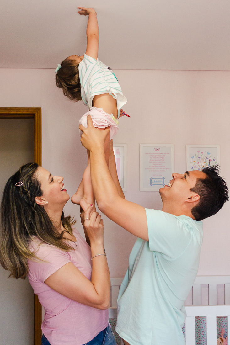 foto de pais brincando com a filha no quarto na cidade de São Paulo.