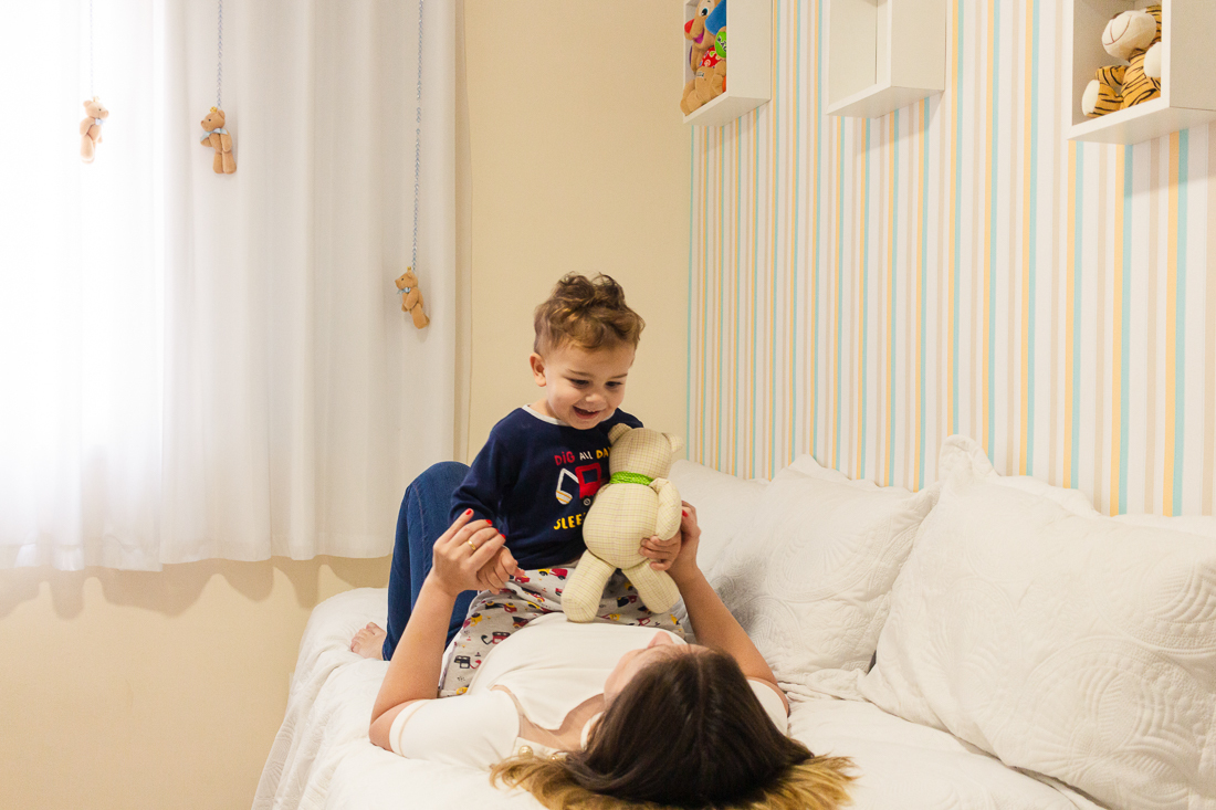 foto de mãe e filho deitados na cama de menino no ensaio de família em casa 