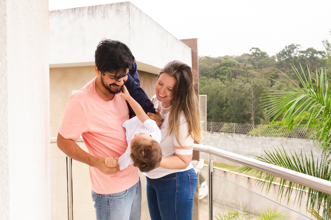 Foto de mãe e filho segurando o filho na sacada de casa na área externa no ensaio de família na cidade de São Paulo