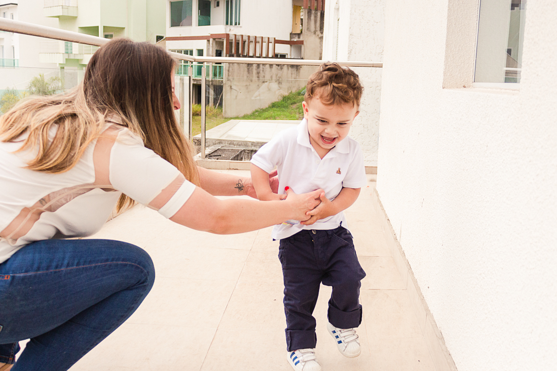 Foto de mãe e filho brincando de pega pega na sacada da casa na área externa no ensaio de família na cidade de São Paulo