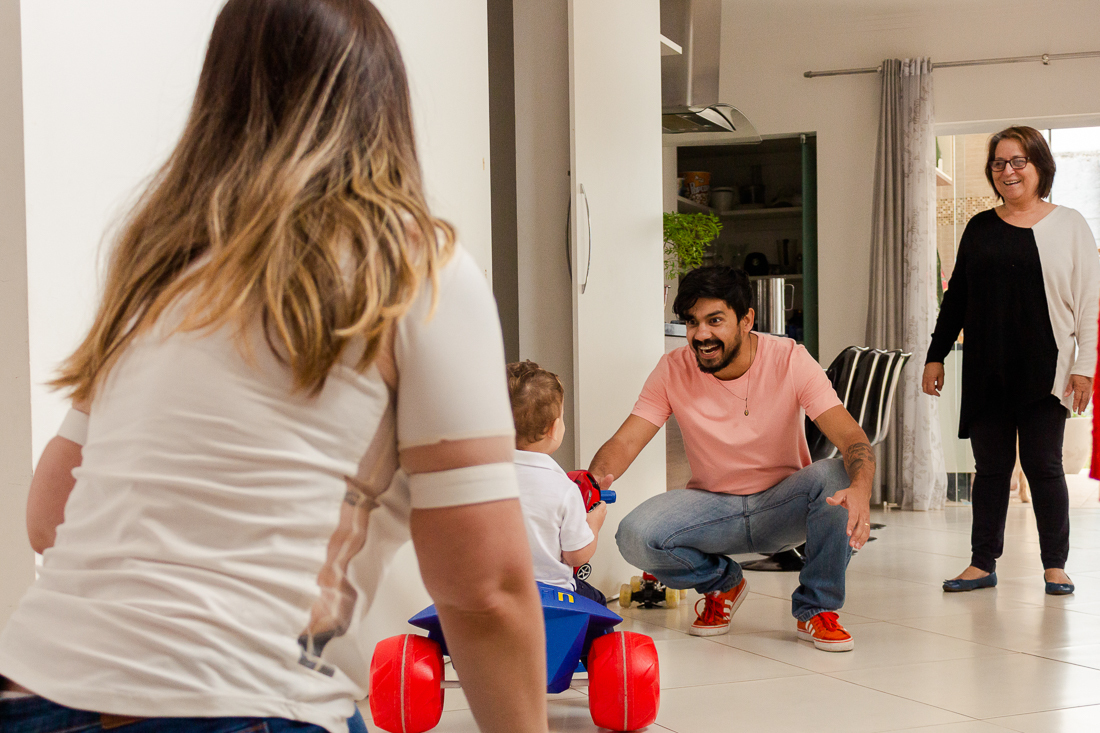 Foto de pais e avó brincando com a criança na sala de casa  no ensaio de família na cidade de São Paulo