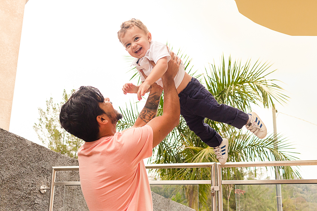 Foto de pai jogando o filho para o alto no ensaio lifestyle em casa na cidade de São Paulo