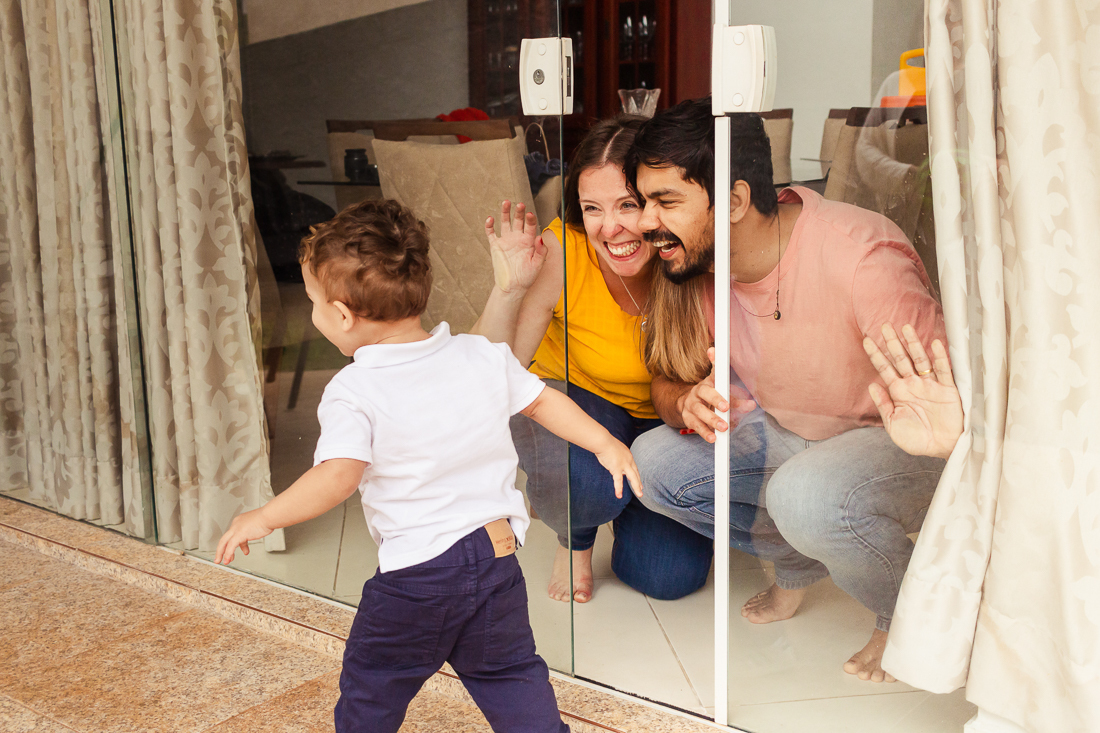 foto de pai e mãe brincando com o filho em casa na porta da sala no ensaio de família na cidade de São Paulo