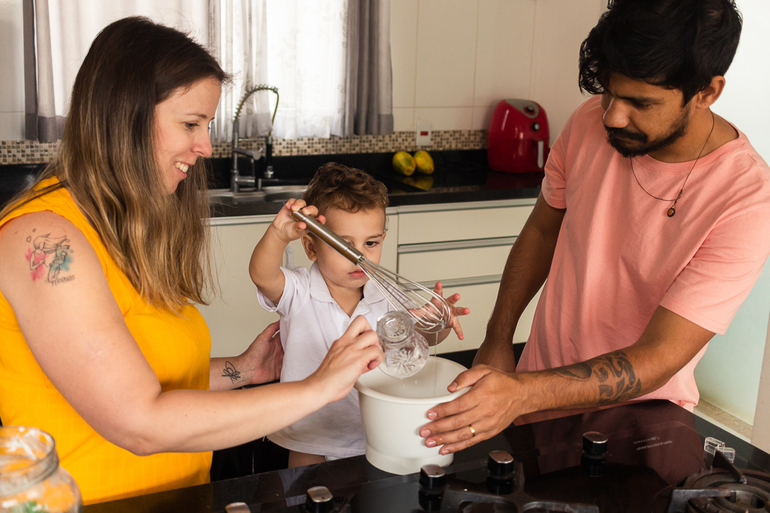 Foto de pais e filho fazendo receita juntos na cozinha de casa no ensaio lifestyle de família na cidade de São Paulo.