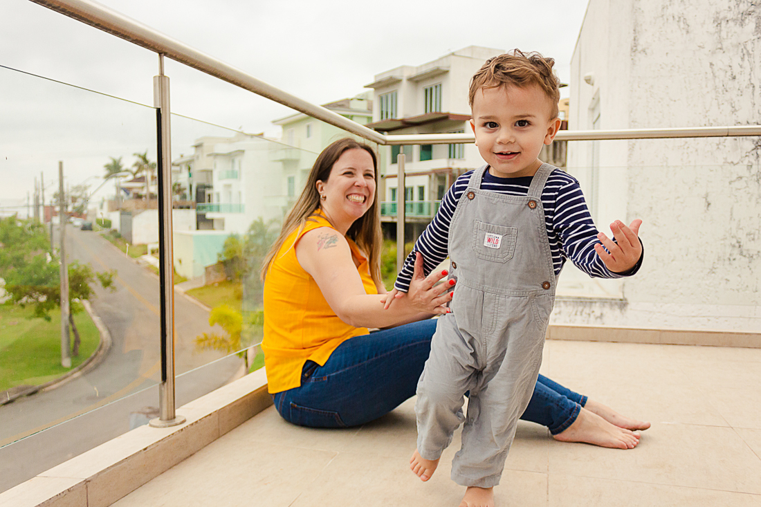 Foto de mãe e filho brincando na sacada da casa na área externa no ensaio de família na cidade de São Paulo