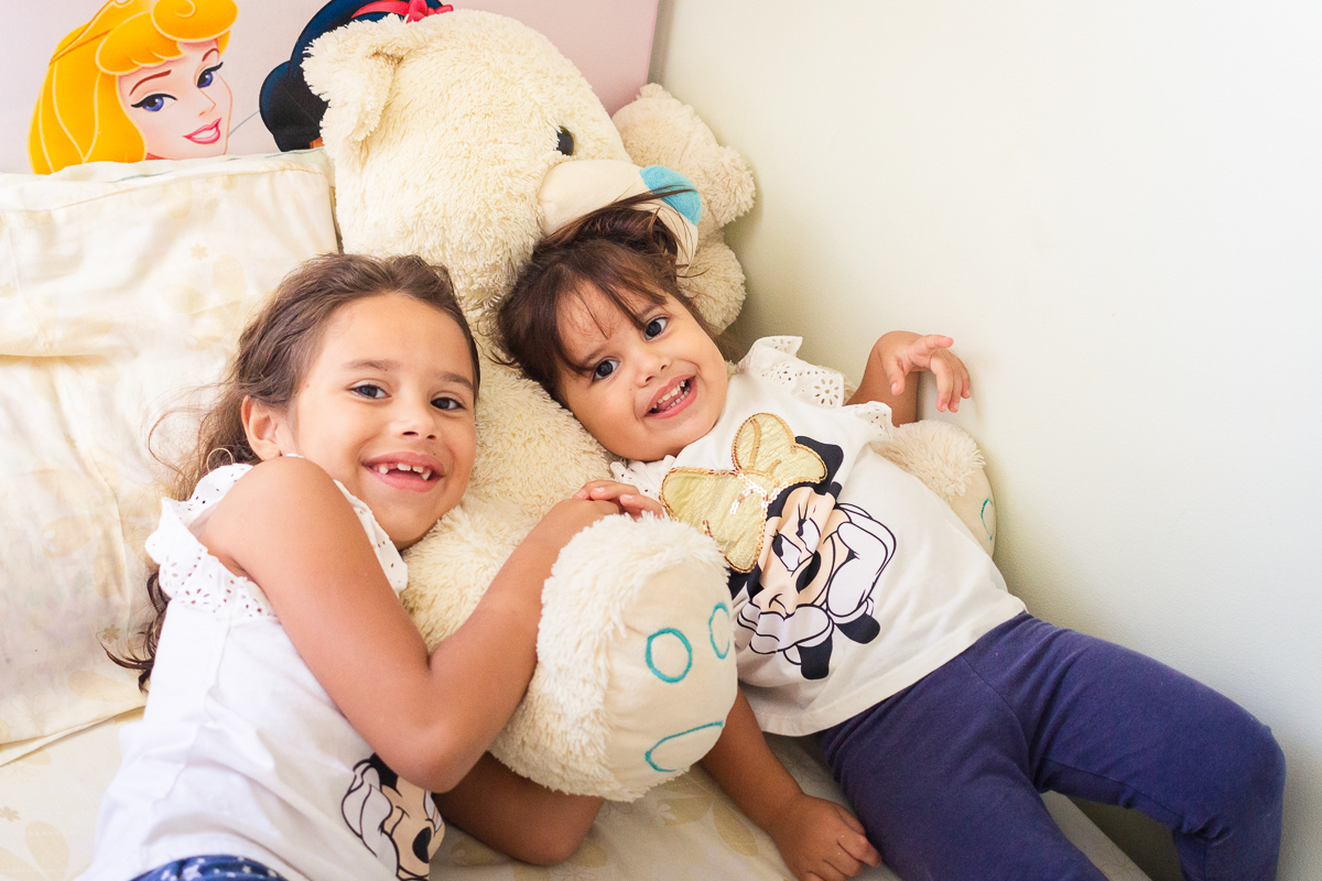 Foto de irmãs se abraçando na cama do quarto no ensaio infantil em casa na cidade de Franco da Rocha- São Paulo