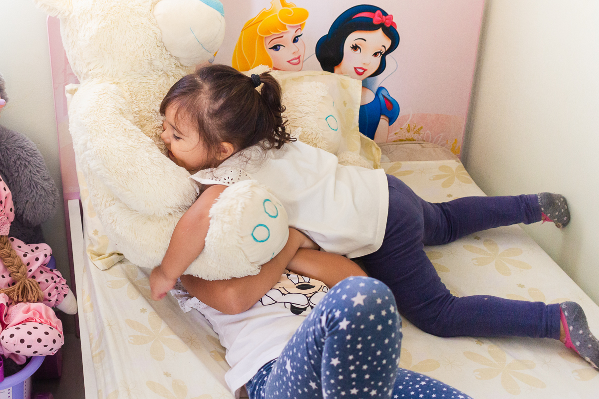 Foto de irmãs se abraçando na cama do quarto no ensaio infantil em casa na cidade de Franco da Rocha- São Paulo