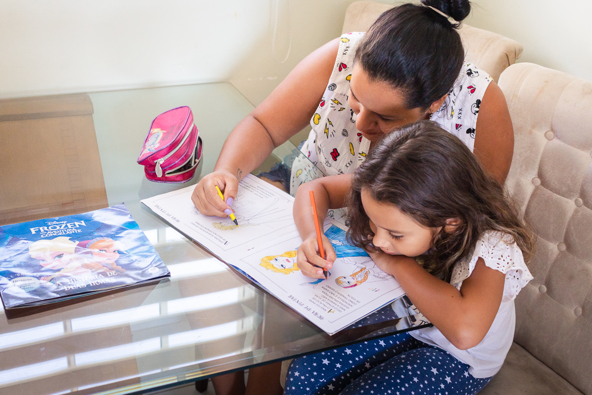 Foto de mãe e filha fazendo lição na mesa de casa no ensaio lifestyle infantil na cidade de Franco da Rocha em São Paulo