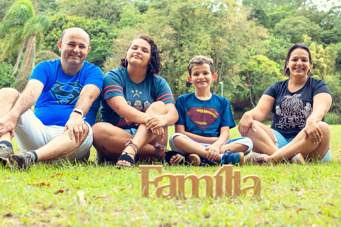 Foto de pais e filhos juntos sentados na grama no ensaio externo lifestyle no parque do Carmo na zona leste de São Paulo.