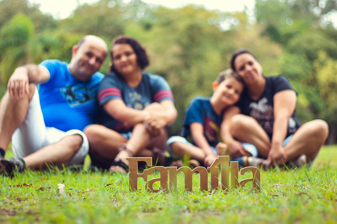 Foto de pais e filhos juntos sentados na grama no ensaio externo lifestyle no parque do Carmo na zona leste de São Paulo.