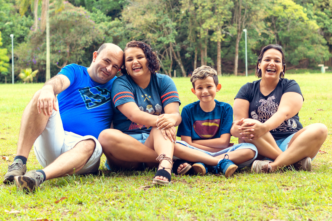 Foto de pais e filhos juntos sentados na grama no ensaio externo lifestyle no parque do Carmo na zona leste de São Paulo.