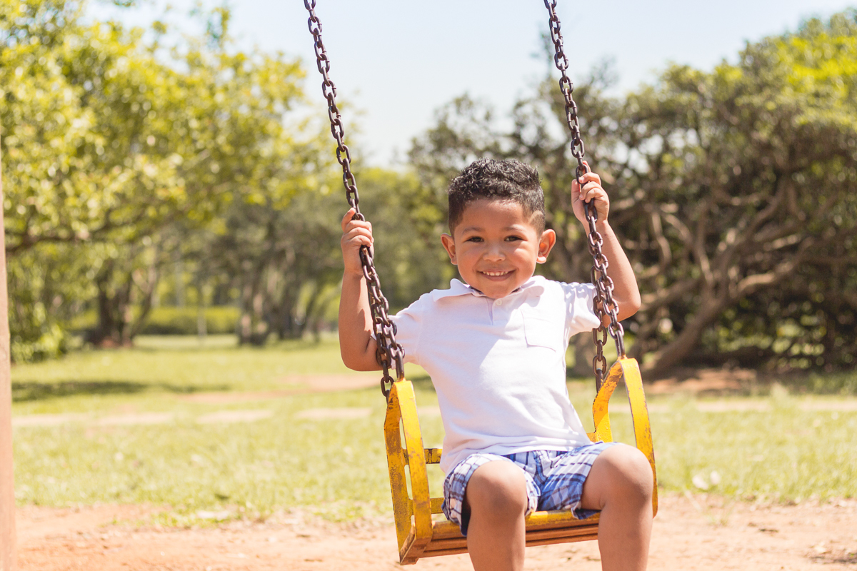 foto de menino brincando no balanço no ensaio infantil no Parque do Ibirapuera na cidade de São Paulo