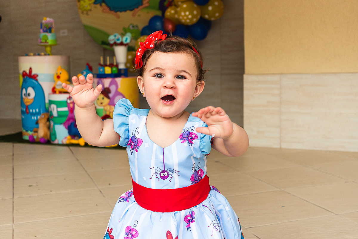 foto da aniversariante com vestido da galinha pintadinha  em frente a mesa da decoração