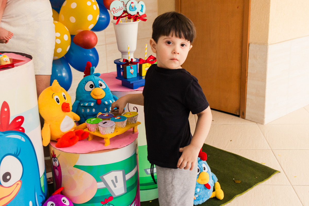 foto de criança na mesa da festa infantil pegando docinho personalizado para comer