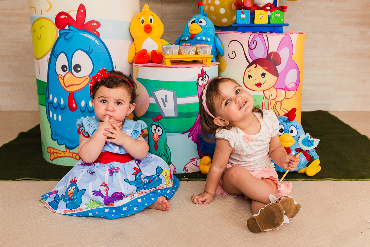 foto de irmãs sentadas no chão em frente a mesa da decoração no aniversario infantil na cidade de São Paulo
