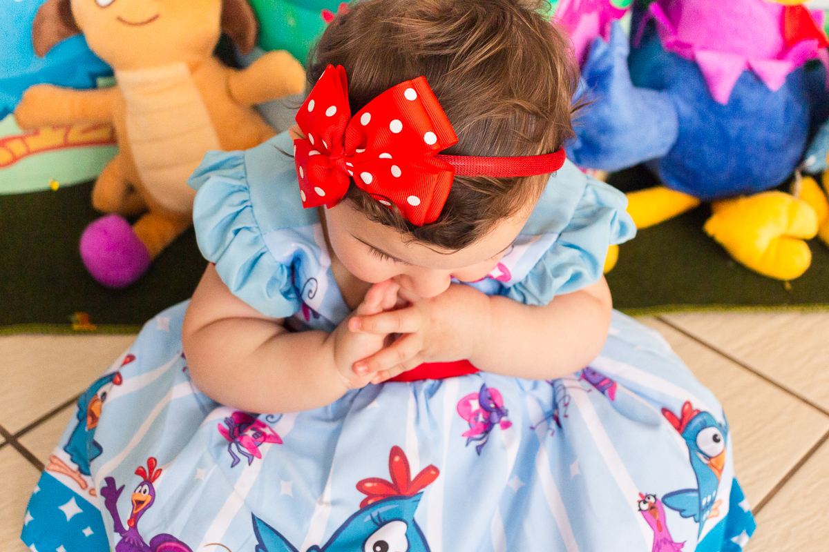 foto detalhe da aniversariante com vestido da galinha pintadinha  em frente a mesa da decoração.