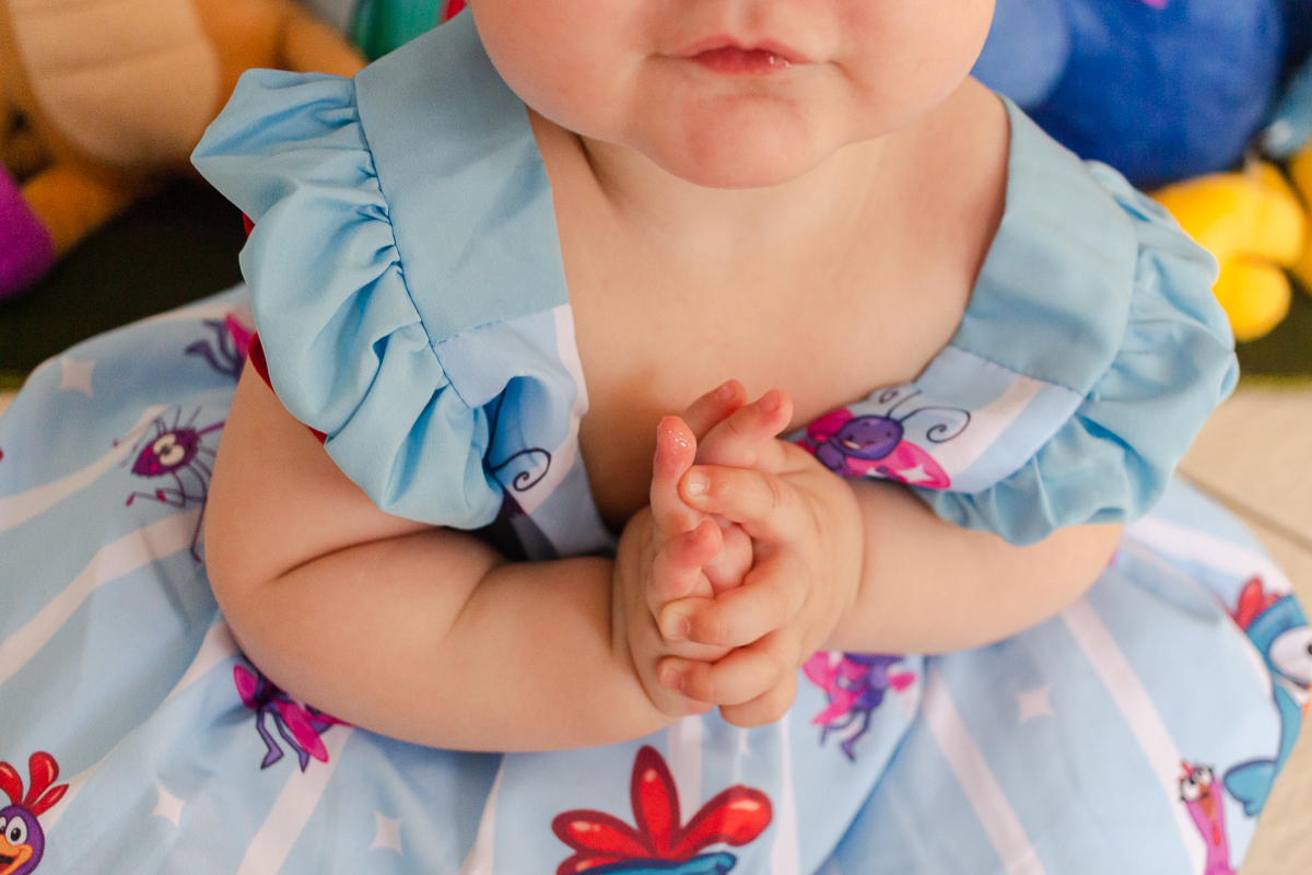 foto detalhe da aniversariante com vestido da galinha pintadinha  em frente a mesa da decoração.