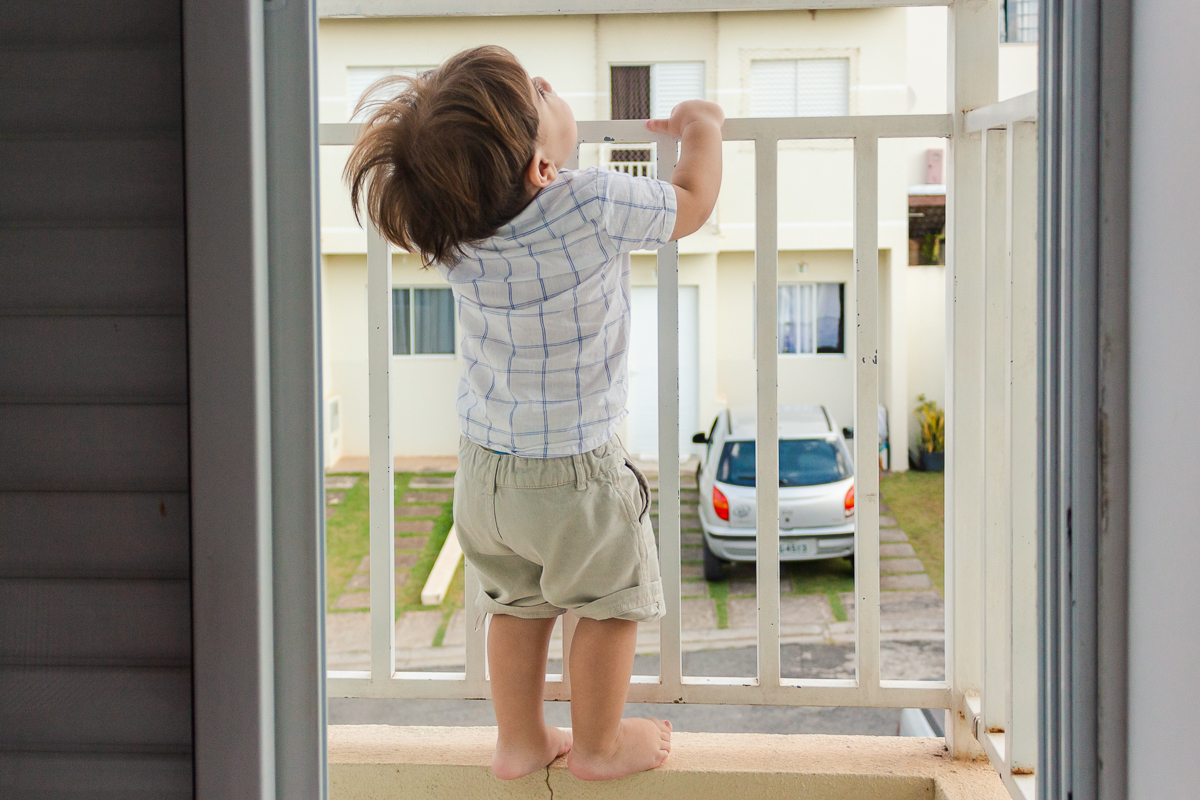 foto de criança na sacada do quarto no ensaio lifestyle infantil na cidade de Franco da Rocha em São Paulo.