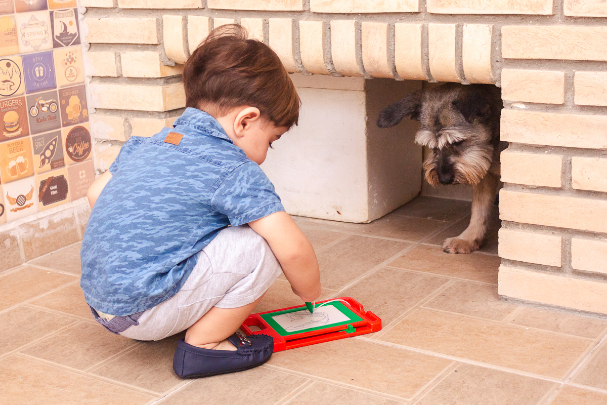 foto de criança brincando cachorro no quintal de casa no ensaio infantil lifestyle em Franco da Rocha na cidade de São Paulo