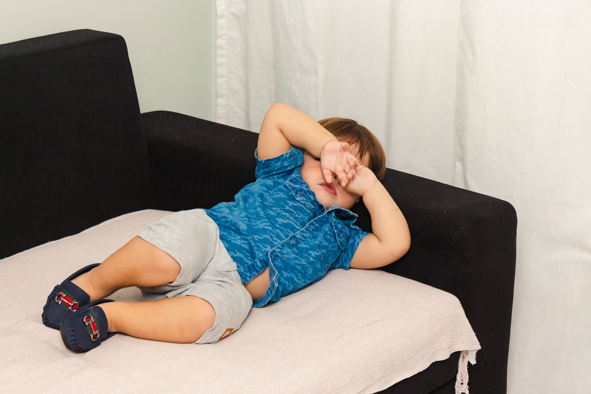 foto de menino deitado com sono no sofá da sala  no ensaio lifestyle infantil na cidade de Franco da Rocha em São Paulo