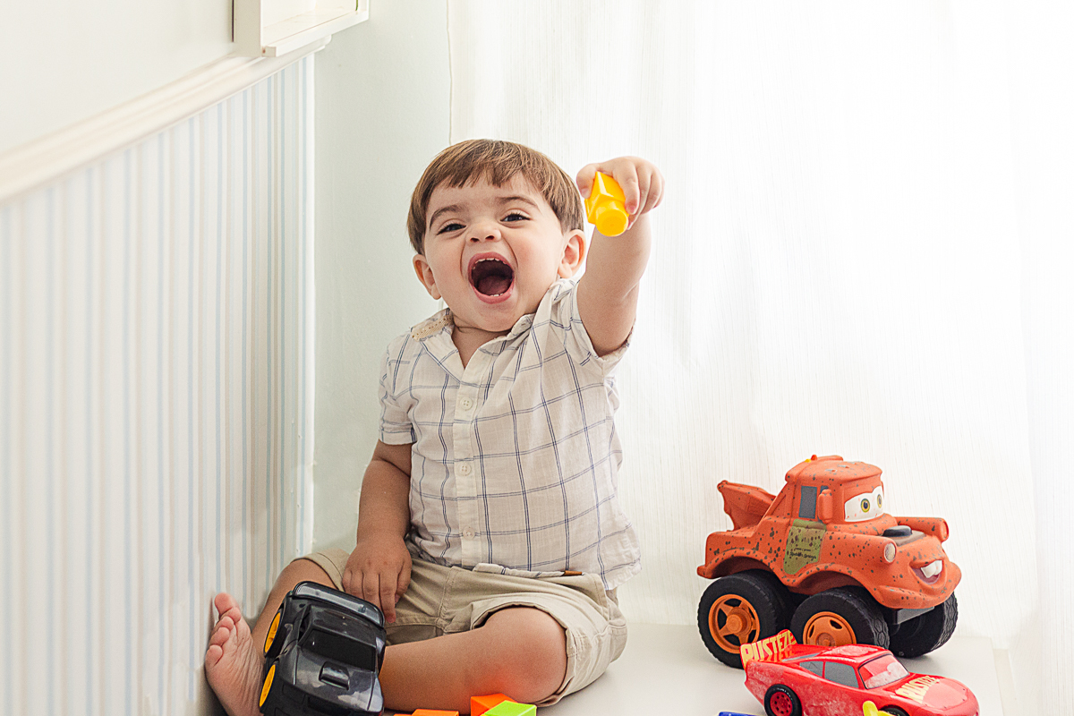 foto de menino brincando com carrinhos dentro do quarto, no ensaio infantil na cidade de Franco da Rocha em São Paulo