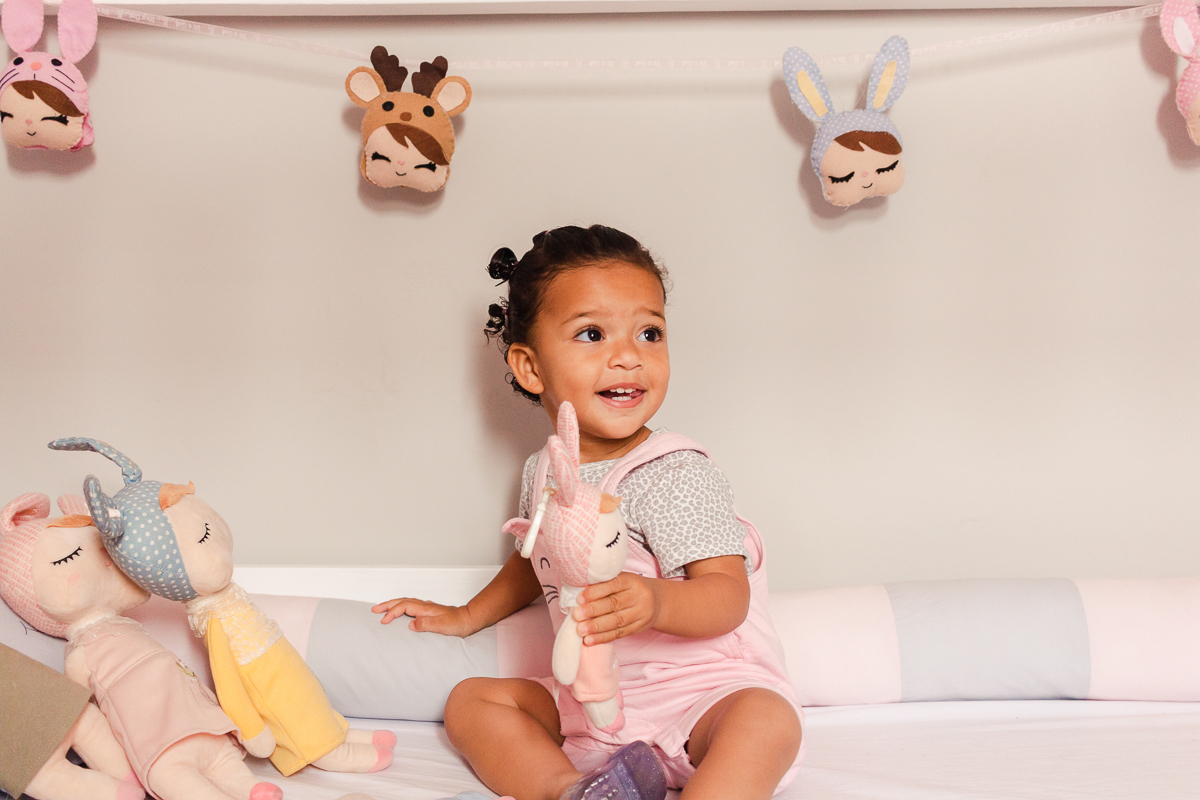 foto infantil de criança sentada dentro do berço com boneca metoo no ensaio de família em casa na zona sul da cidade de Sp