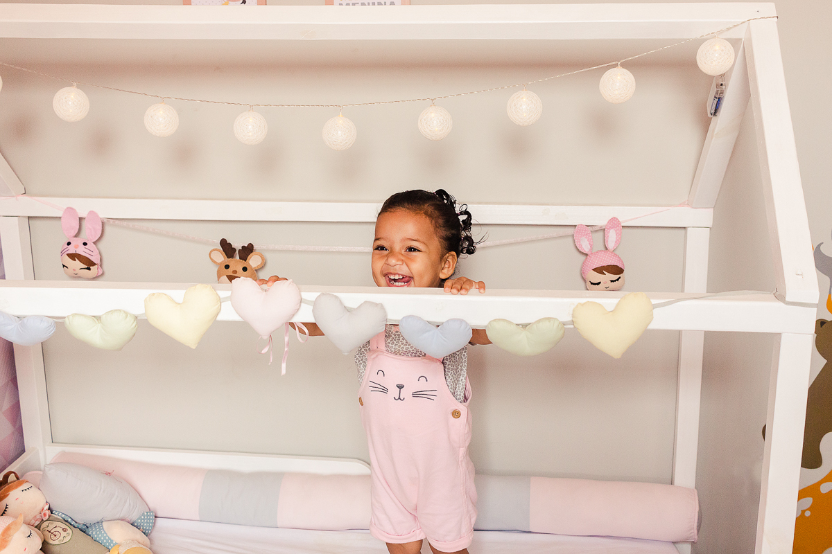 foto de menina dentro do berço em pé sorrindo, no ensaio de família em casa na zona sul da cidade de Sp cidade de Sp