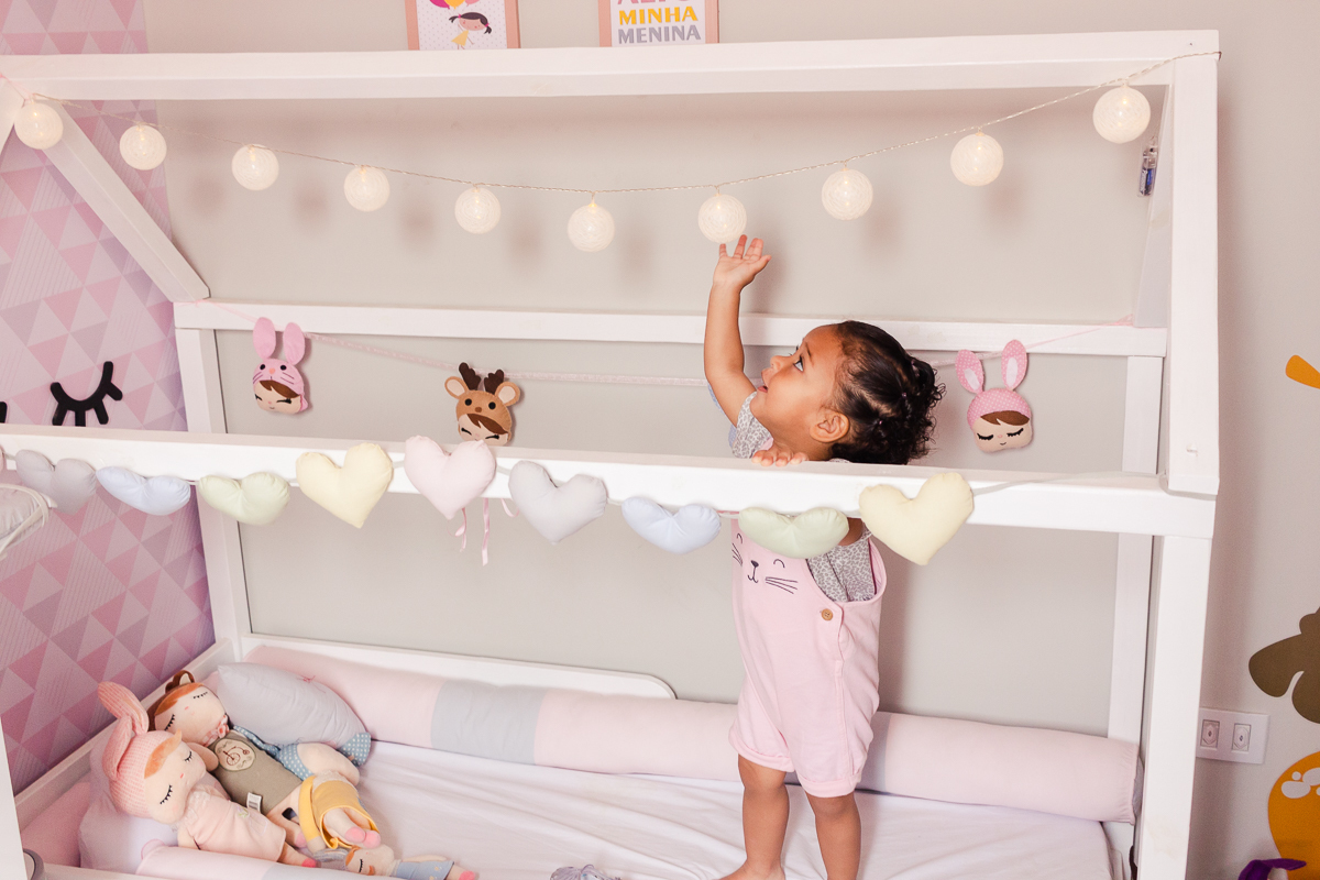foto de menina dentro do berço em pé sorrindo, no ensaio de família em casa na zona sul da cidade de Sp cidade de Sp