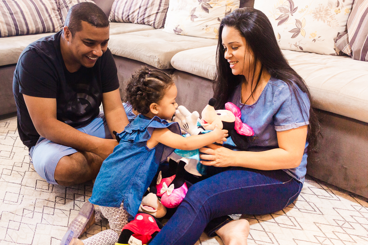 foto de família brincando no chão da sala com bonecos da Disney no ensaio lifestyle em casa na cidade de SP